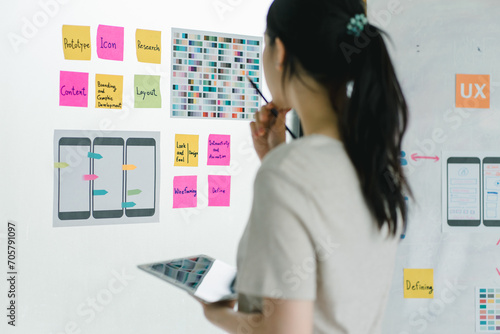 Asian ux designer evaluating app prototypes with color swatches.