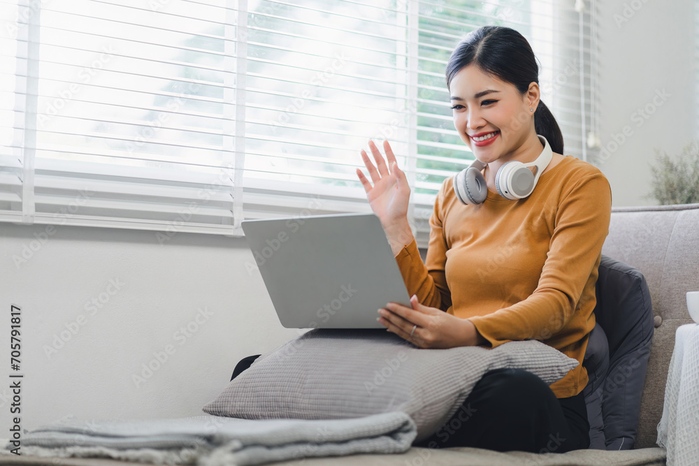 Happy asian woman waving during a video call on laptop at home. Happy asian woman waving during a video call on laptop at home.