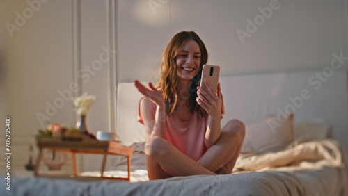 Smiling girl waving call ending conversation. Happy teenager resting bed talking photo