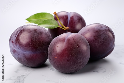  a group of plums sitting on top of a marble counter top with a green leaf on top of one of the plums and the plums on the other.