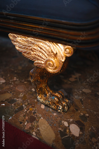 Furniture details. Carved wooden lions paw with gold wings.