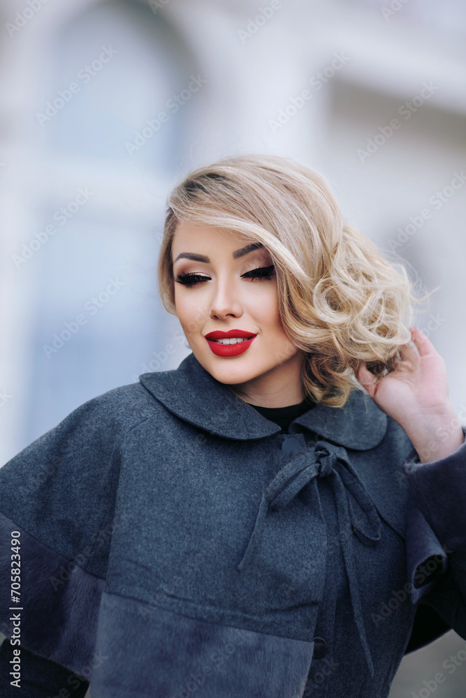 Fototapeta premium stylish girl in pin-up style with a fashionable hairstyle in an autumn coat against the backdrop of the city.