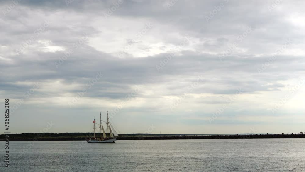 The white sailing ship goes to sea. A large ship with sails leaves the bay. Nordic landscape. Sailing rigate on a cloudy day. The holiday of the sea in Klaipeda. A yacht sails next to a large ship. The white sailing ship goes to sea. A large ship with sails leaves the bay. Nordic landscape. Sailing rigate on a cloudy day. The holiday of the sea in Klaipeda. A yacht sails next to a large ship.