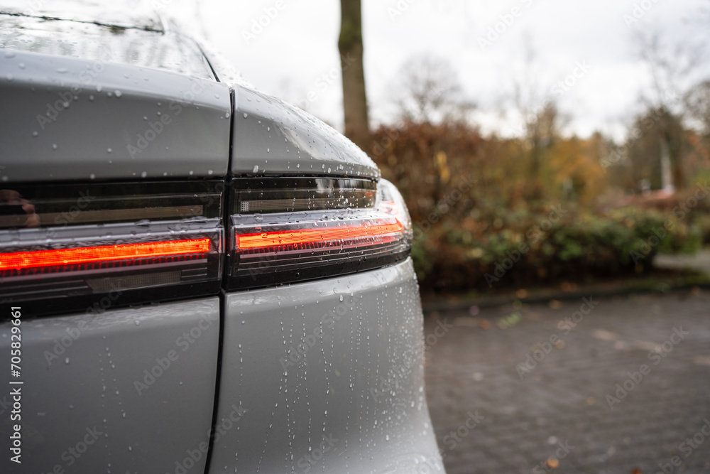 Modern LED taillight, after a rain shower on a gray new car