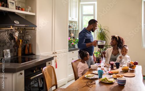 Happy family eating breakfast at kitchen table photo