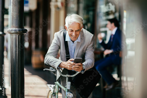 Senior businessman using smartphone during bike commute in city photo