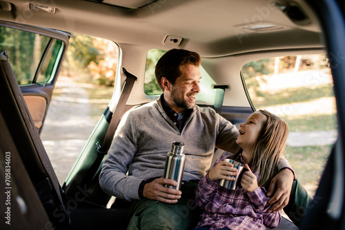 Father and daughter laughing together with thermos in car photo