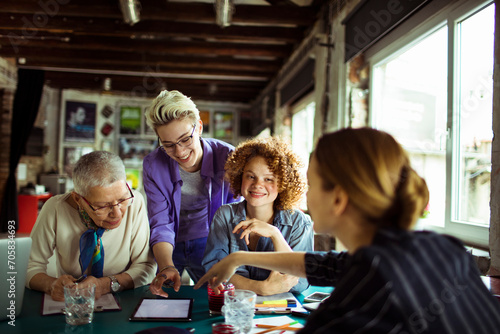 Diverse group of women in a meeting discussing over digital tablets in a workshop photo