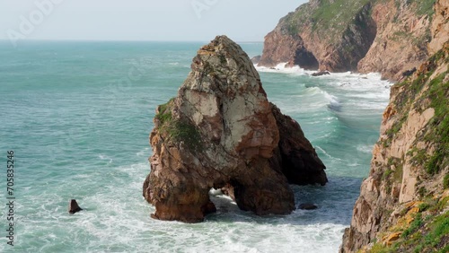 Unique textured rock through which sea waves pass is located near shore. Tourism and travel. View from above. Recreation and entertainment. Beautiful nature. Meditation and relaxation. 4k footage.