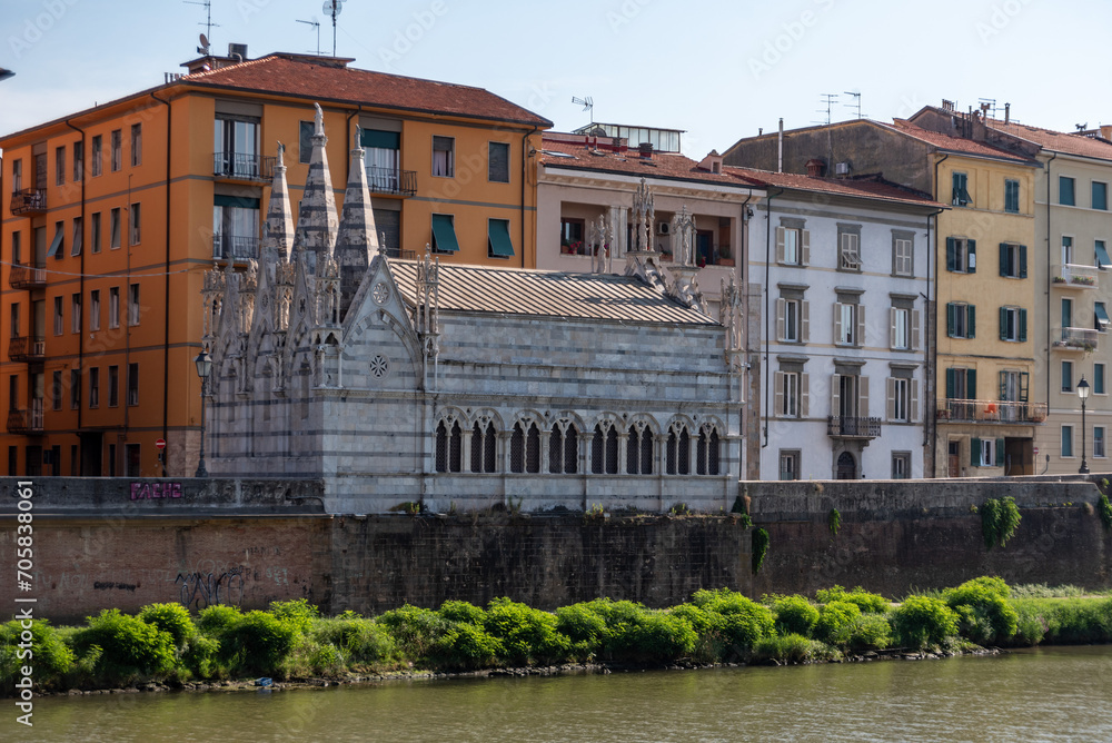 Old picturesque houses at the Arno river waterfront in Pisa, the little church Santa Maria della Spina in the foreground