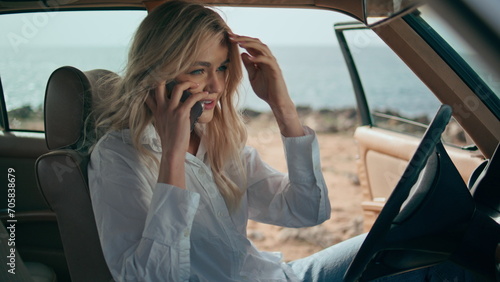 Woman driver talking telephone sitting in retro car at sunny ocean coast closeup