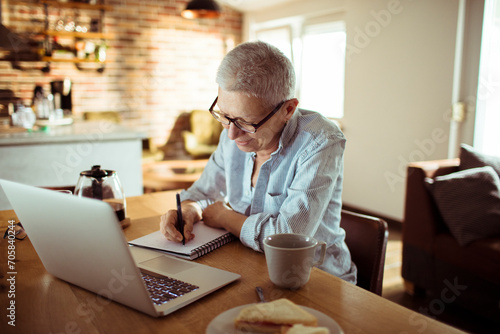Senior woman working from home and taking notes