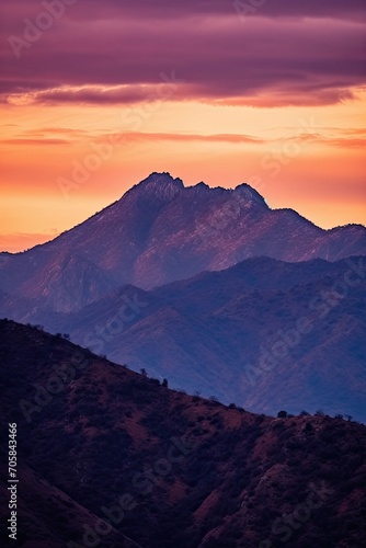 Silhouette of jagged mountain peaks with the sky painted in shades of orange, pink, and purple