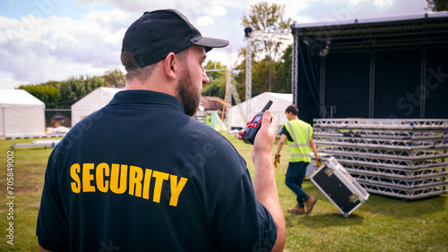 Rear View Of Security Team At Outdoor Stage For Music Festival Or Concert Talking Into Radio photo