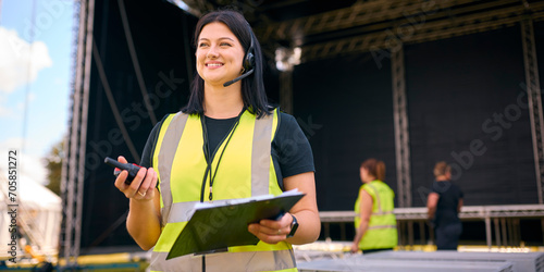 Portrait Of Female Production Worker Setting Up Outdoor Stage For Music Festival Or Concert photo
