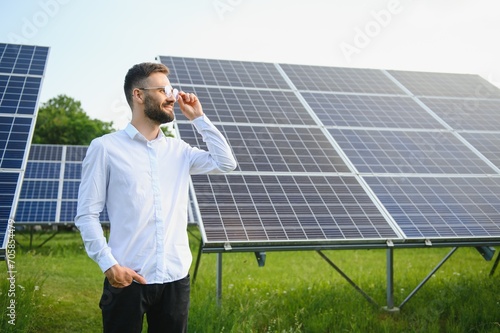Solar power plant. Man standing near solar panels. Renewable energy. photo