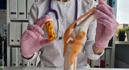 фотографія Doctor is holding medical tablets and knee joint of leg