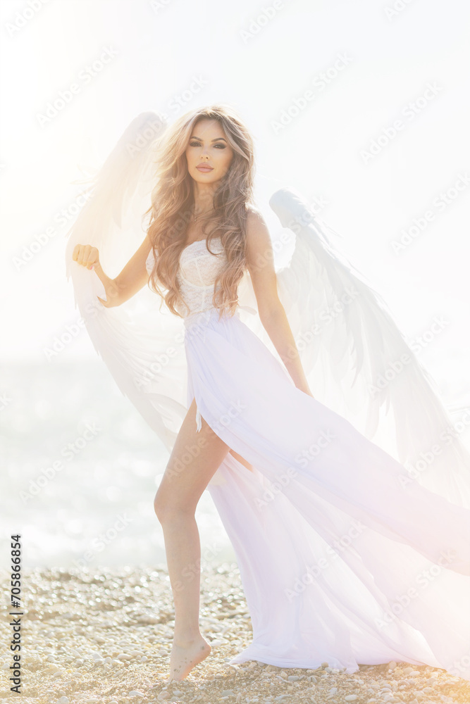 beautiful girl with angel wings is walking along the seashore