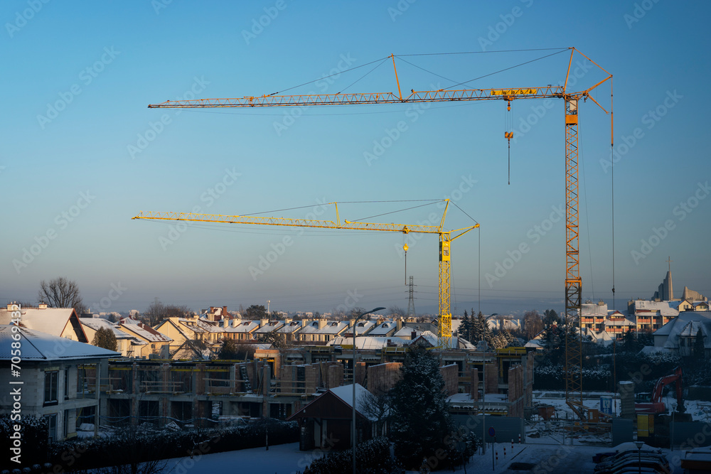 Construction of row houses (buildings under construction) in fastest growing economy of European Union - Poland. Rzeszow during winter sunset. Cranes concept. 