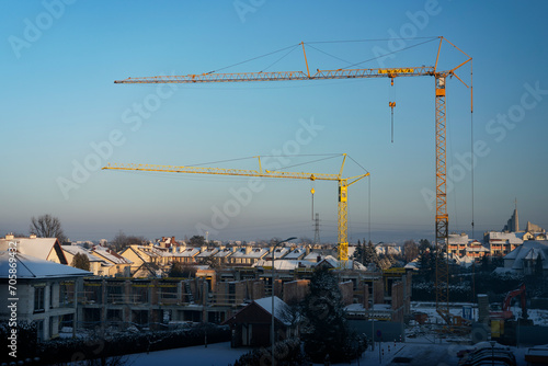 Construction of row houses (buildings under construction) in fastest growing economy of European Union - Poland. Rzeszow during winter sunset. Cranes concept. 