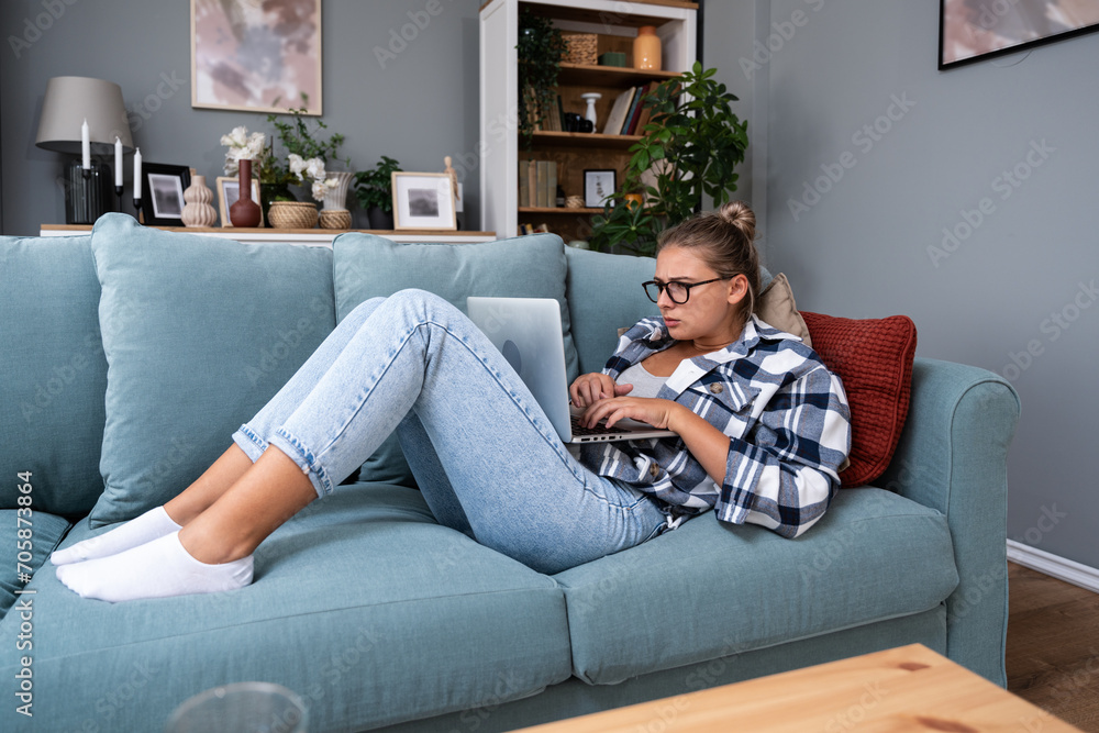 Young freelance business woman working at home on laptop as product strategy expert. Female expatriate remote work on internet on computer online for foreign company as web developer
