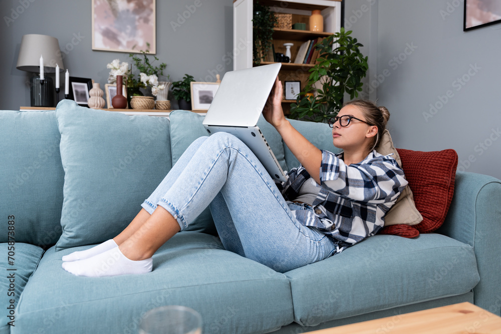 Young freelance business woman working at home on laptop as product strategy expert. Female expatriate remote work on internet on computer online for foreign company as web developer