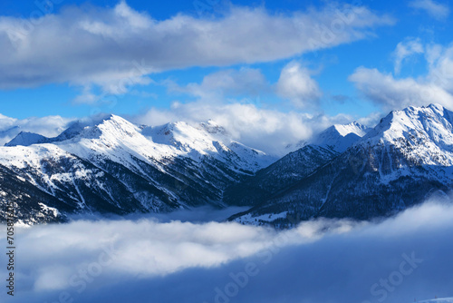 Mountain covered with snow and fog. Alpine landscape in Italy, Europe. Snow-capped mountains against blue sky