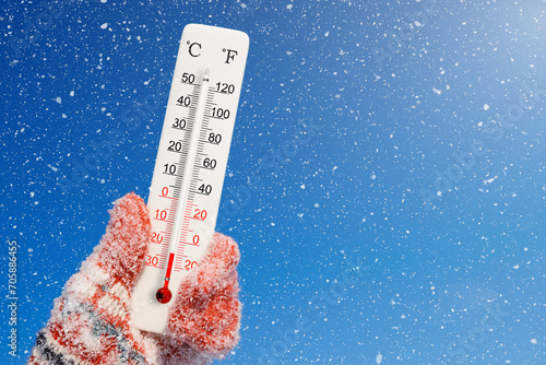 White celsius scale thermometer in hand. Ambient temperature minus 23 degrees celsius photo
