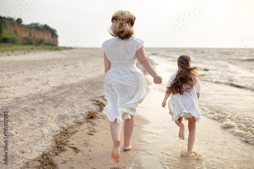 Mother and daughter running by the sea