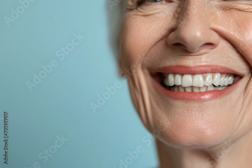Smiling elderly person with smooth white teeth implants. Close up portrait of female mouth on pastel blue background, banner with copy space. Positive senior woman photo