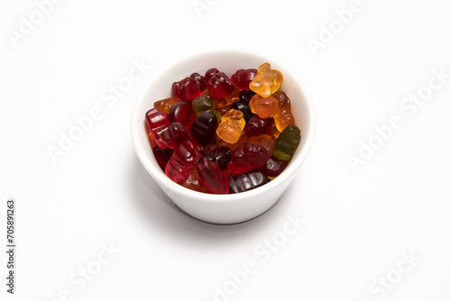 Colorful gummy candies in a white cup on a white background