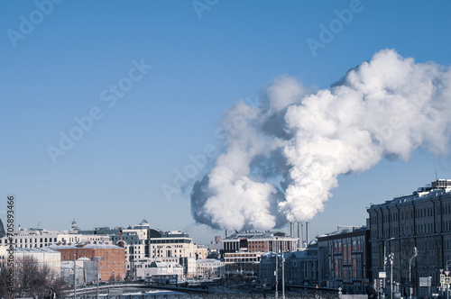 Smoke from cities chimneys in winter on a blue sky background
