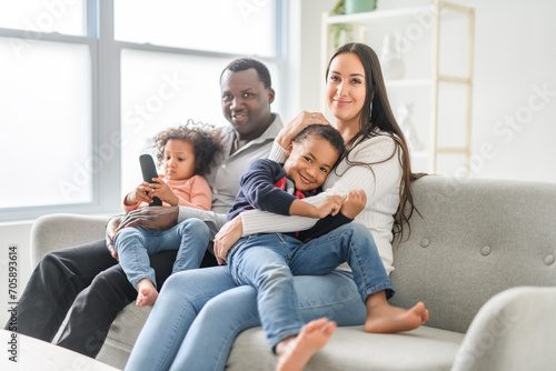 family with boy and girl child posing on photo shooting, sitting on couch and watching tv