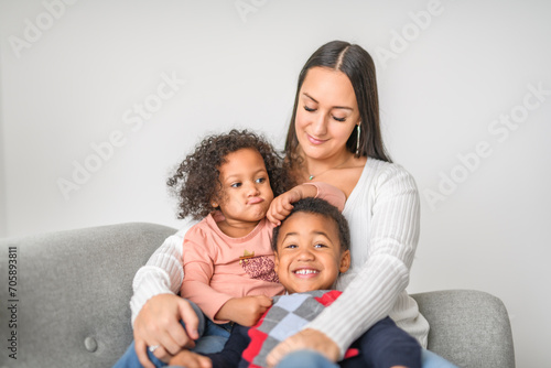 family with boy and girl child posing on photo shooting, sitting on couch