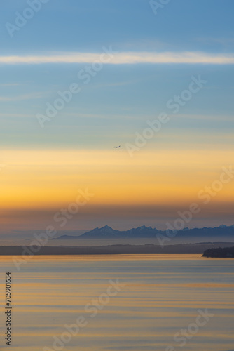 A colorful sunset lights up the clouds in the sky over the Pacific Northwest with mountains in the background