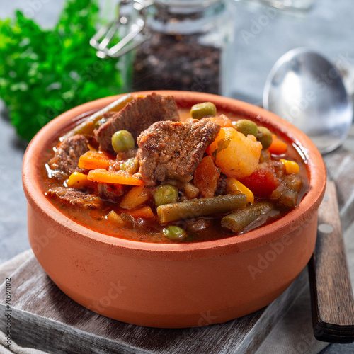 Beef stew with potato, green beans, carrot, peas and corn, in ceramic bowl, square format