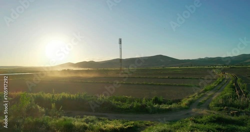 Aerial view to the alone TV, radio mobile tower in field under sunset sky