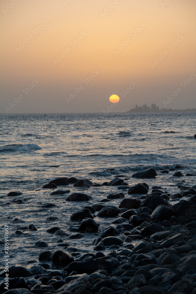 Beautiful orange sunset over the sea with stones on the beach