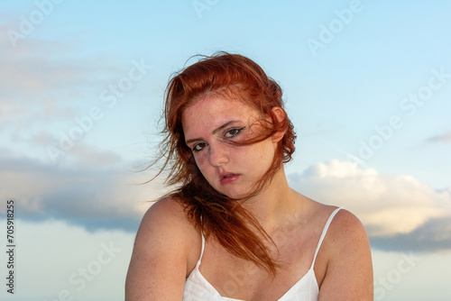 Young woman with windblown hair and sky