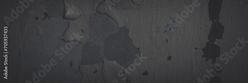 Dark wide panoramic background. Peeling paint on a concrete wall. Faded dark texture of old cracked flaking paint. Weathered rough painted surface with patterns of cracks. Shaded background for design photo