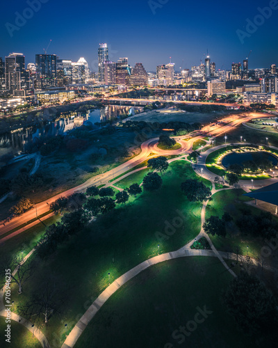Austin skyline captured post-sunset from a drone perspective. Lady Bird Lake reflects city lights, showcasing dynamic urban charm. Aerial view of iconic landmarks and vibrant cityscape, perfect for cr