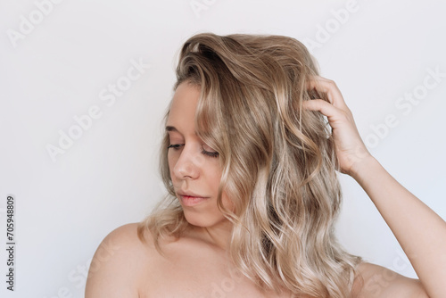 Young blonde woman with voluminous wavy hair isolated on a white background. Result of coloring, highlighting, perming. Beauty and fashion