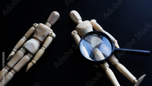 Tableau sur toile Wooden mannequins and a magnifying glass on a dark background