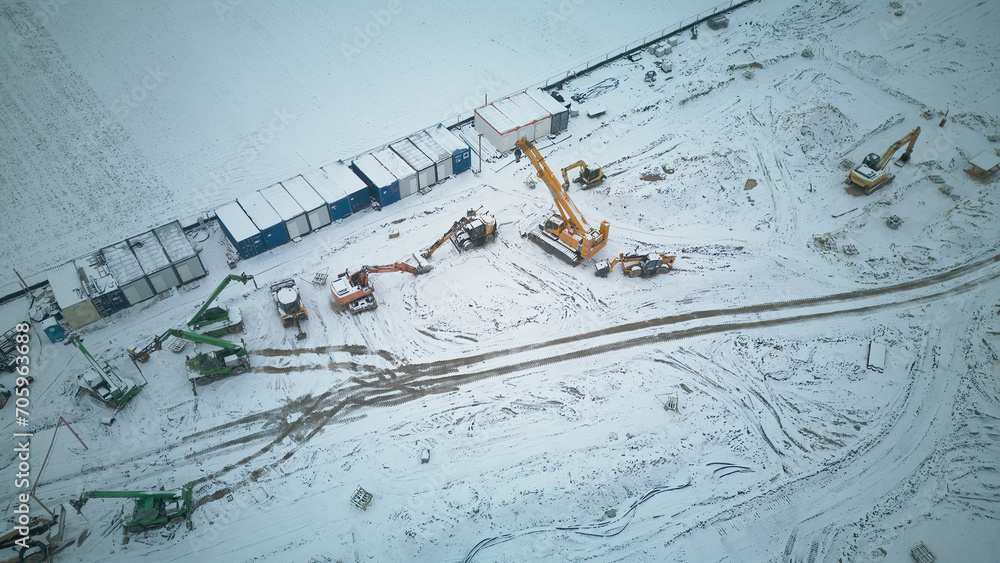 Aerial view on construction site, winter in the morning, construction machines and foundations of a new building, concept for work in difficult conditions, recession, construction. Aerial view on construction site, winter in the morning, construction machines and foundations of a new building, concept for work in difficult conditions, recession, construction.