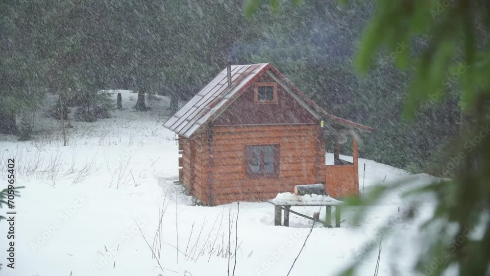 Snow falling on mountain forest and pine log house. Tree branch in the foreground Snow falling on mountain forest and pine log house. Tree branch in the foreground