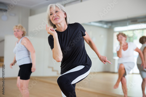 Group of three mature women performing modern dance in exercise room. photo
