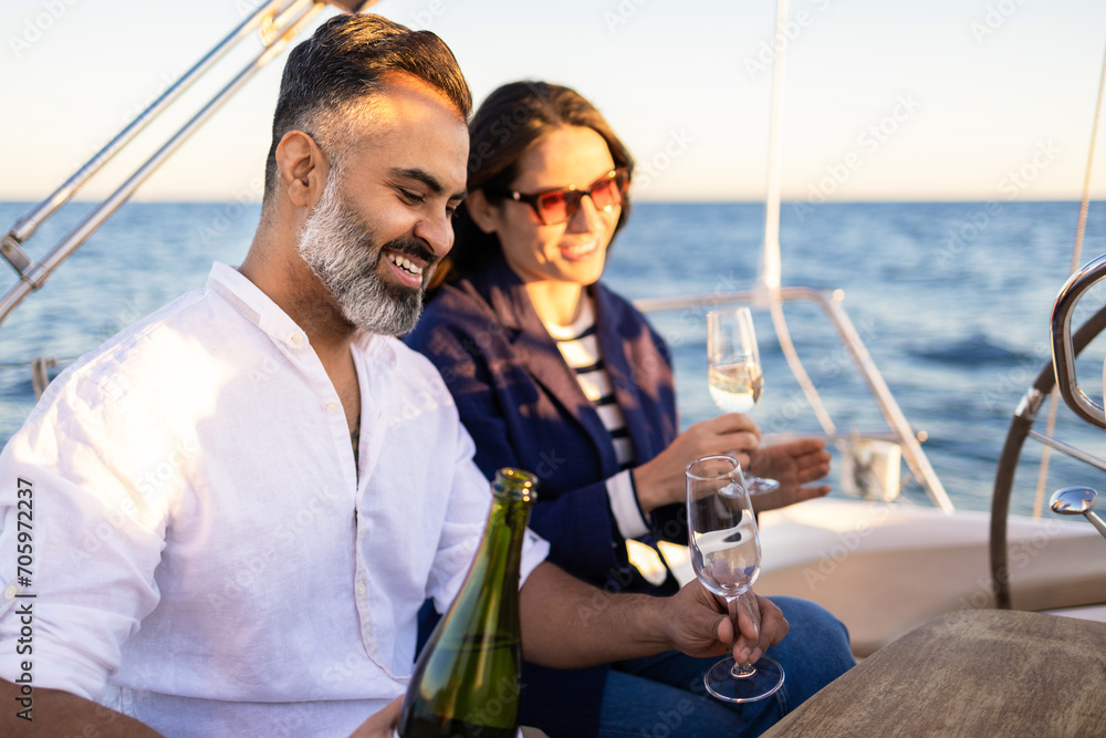 Couple pouring champagne into wineglasses on yacht Couple pouring champagne into wineglasses on yacht