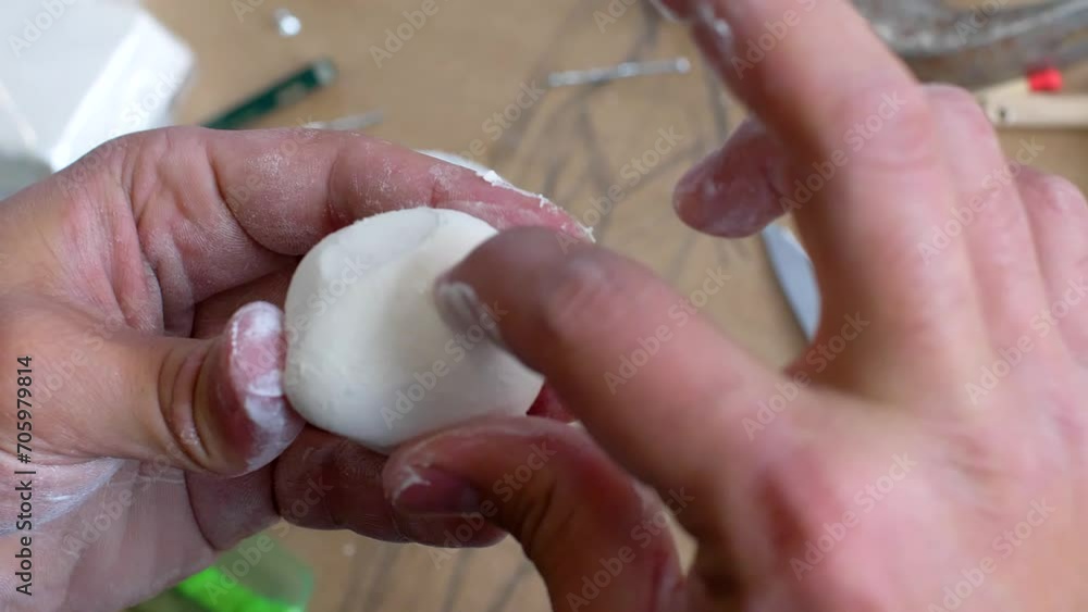 Delve into the world of craftsmanship with a close-up view of a sculptor's skilled fingers delicately carving on a small white ball of clay. Delve into the world of craftsmanship with a close-up view of a sculptor's skilled fingers delicately carving on a small white ball of clay.