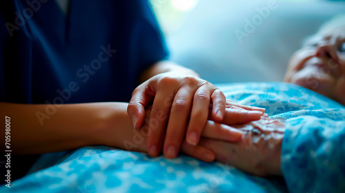 Close up of a nurse holding the hands of an elderly patient. Concept of terminal care at hospitals or hospices. Shallow field of view.
