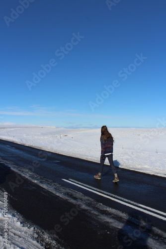 Girl travelling alone in Iceland, walking on a road in the snow